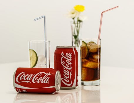 Coca-Cola cans with ice and lime on a table, fresh and invigorating.