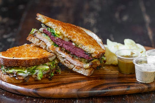 A delicious sandwich with roast beef, lettuce, and sauces on a wooden board, perfect for a gourmet meal.