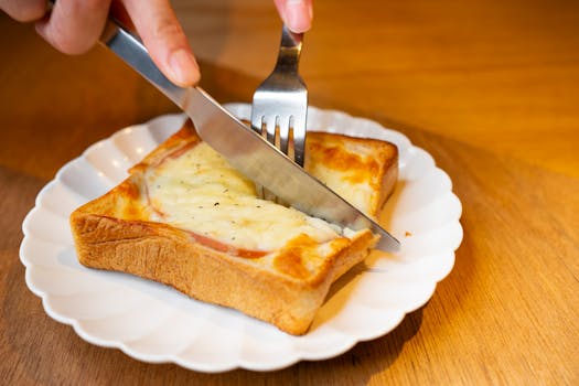 Close-up of a grilled cheese toastie being cut open, served on a white plate in Tokyo.