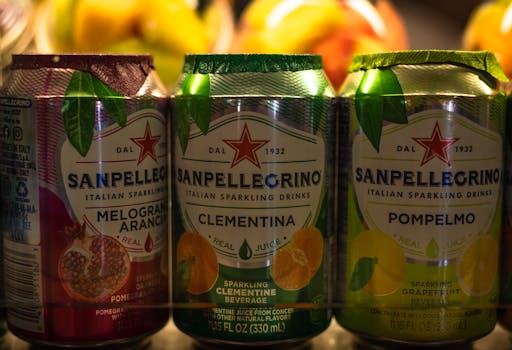 Assorted Sanpellegrino sparkling drink cans in close-up showcasing flavors like clementina and pompelmo.